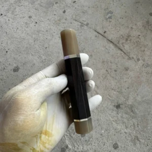 African blackwood handle with a pale horn front ferrule, separate pale horn rear end cap, and thin silvery spacers, held in a white glove.