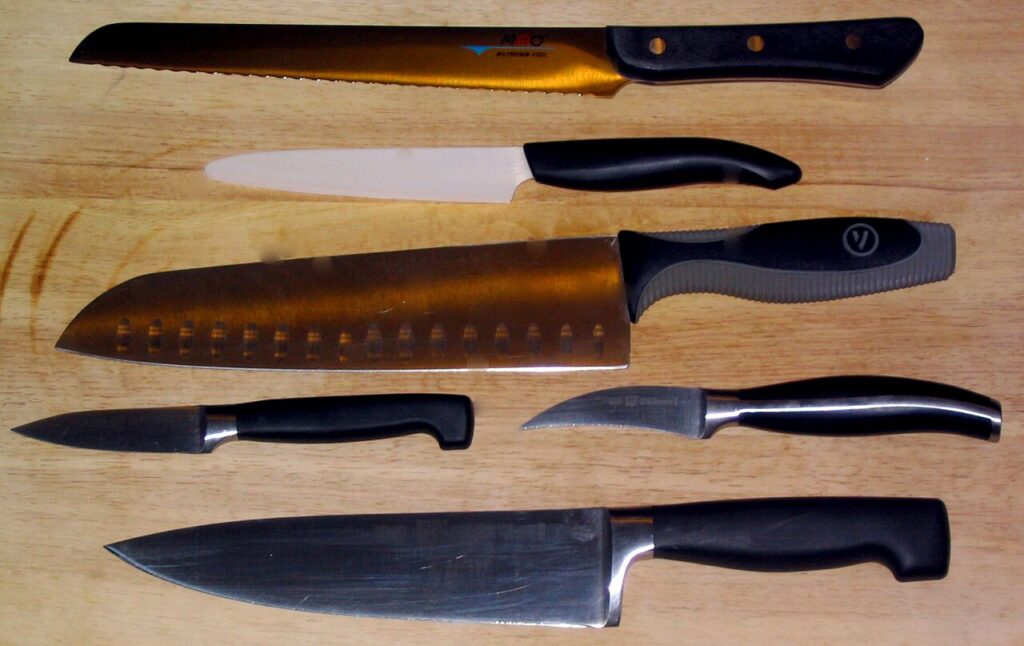 White-bladed ceramic utility knife arranged with several steel kitchen knives