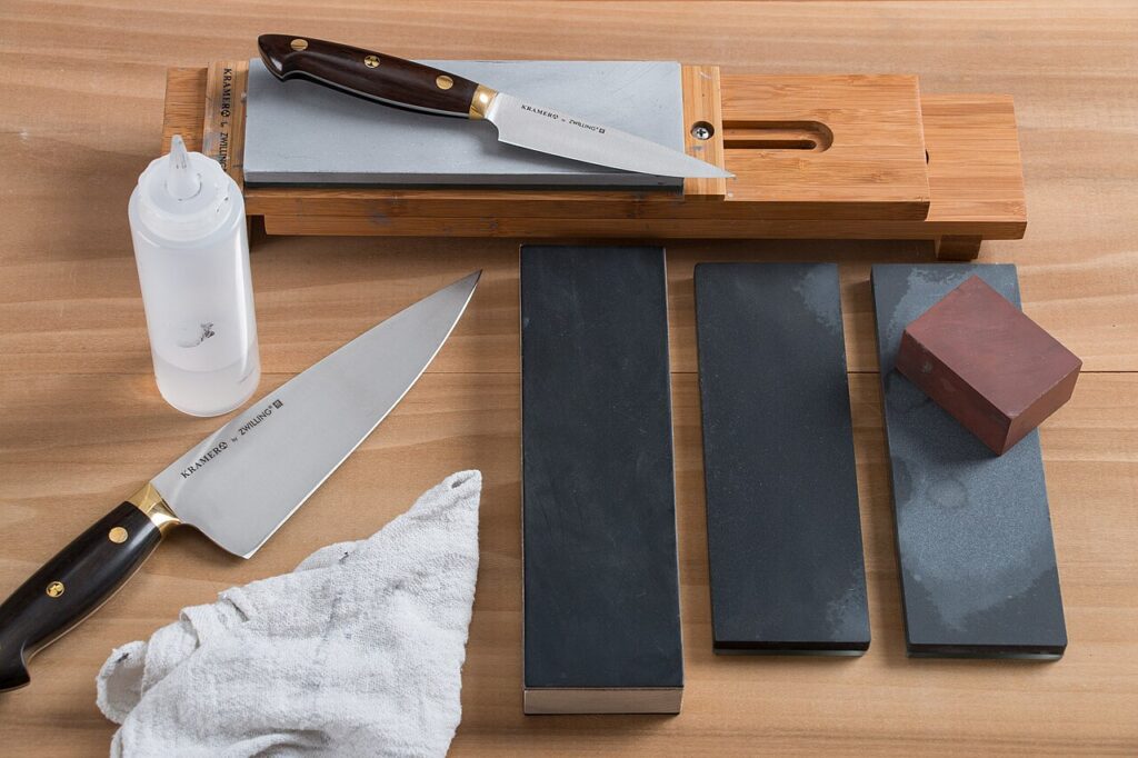 Sharpening setup with knives, bench stones, water bottle and a small block at right