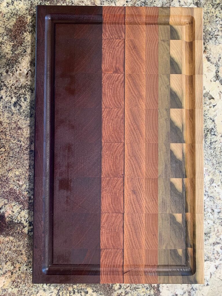 A rectangular end-grain cutting board with contrasting wood blocks and a perimeter groove.