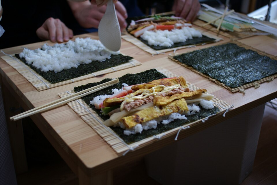 Nori, rice and fillings arranged on bamboo mats before rolling sushi