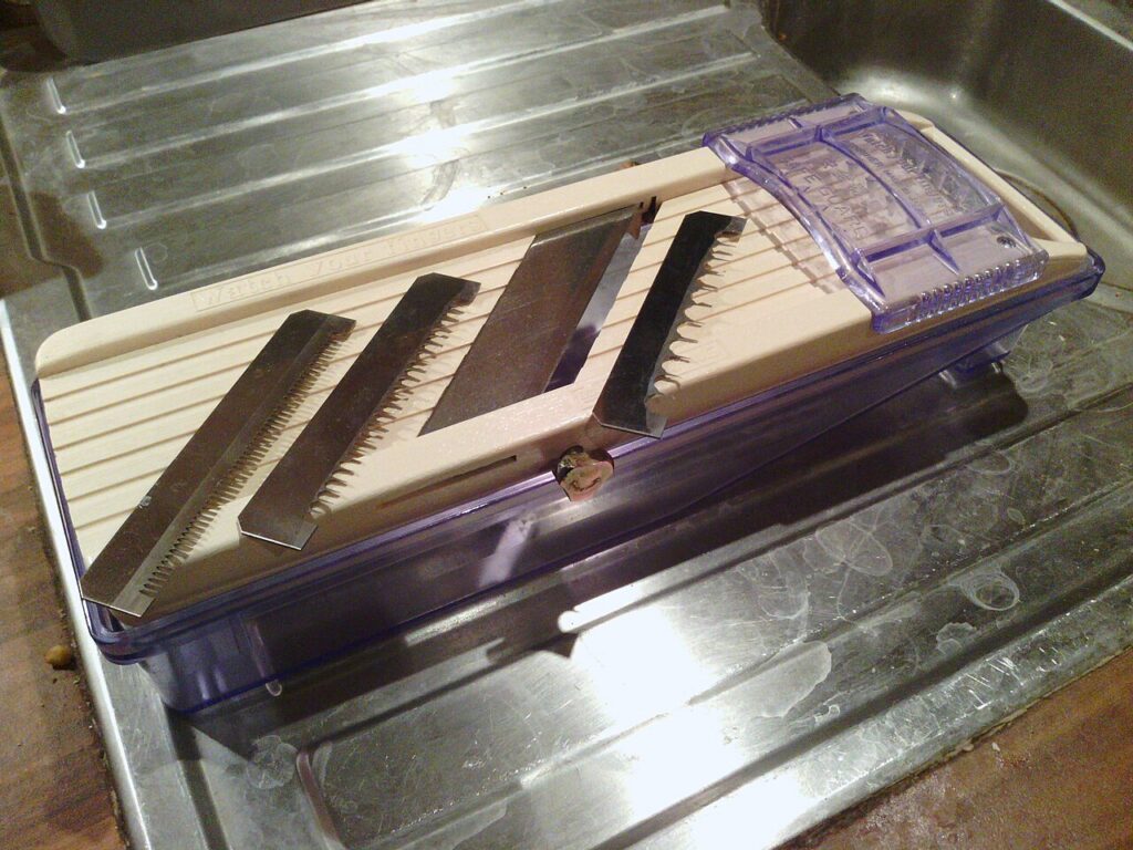 A Benriner slicer with three removable comb blades and its food holder laid out.