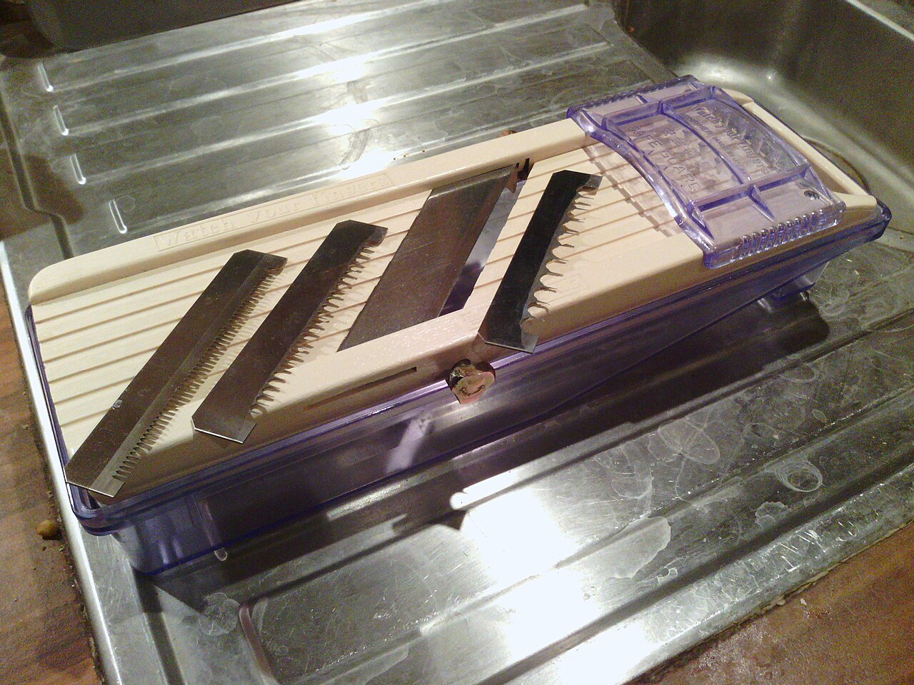 A Benriner slicer with three removable comb blades and its food holder laid out.