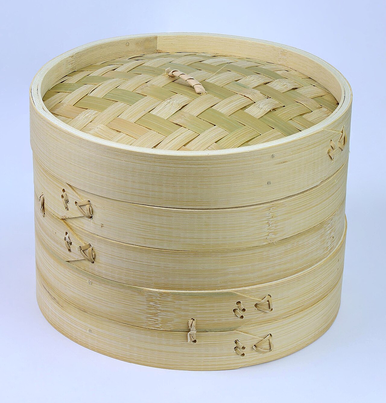 Two bamboo steaming baskets stacked beneath a woven lid