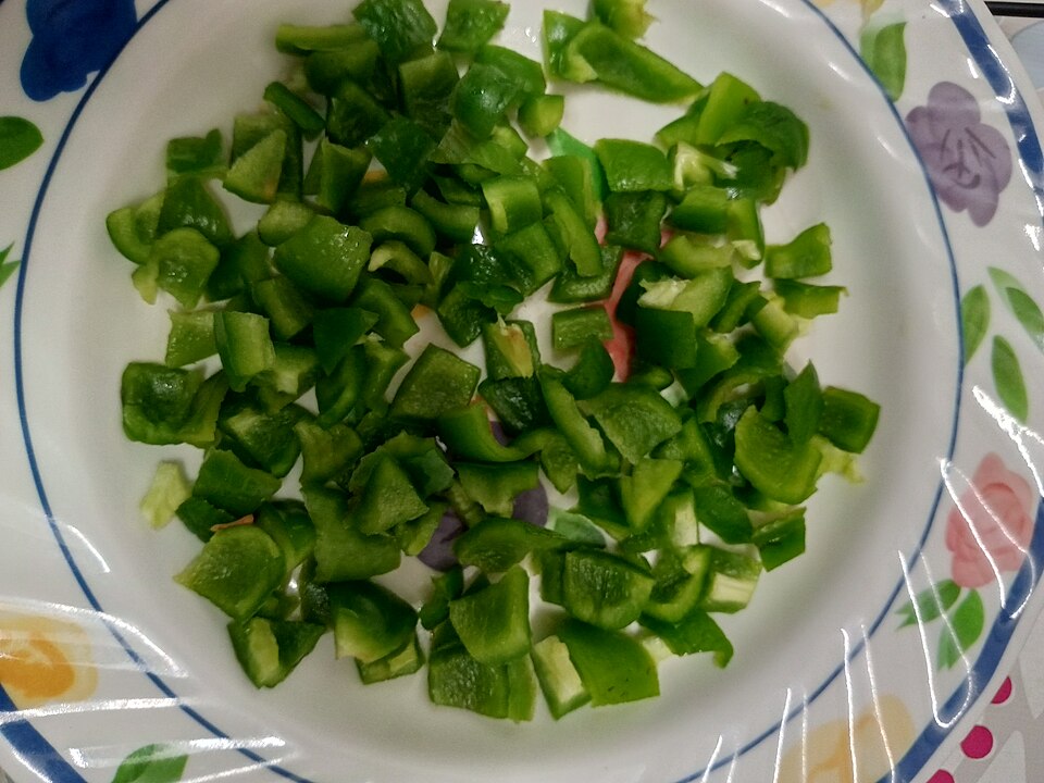 Green bell pepper cut into small pieces on a plate.