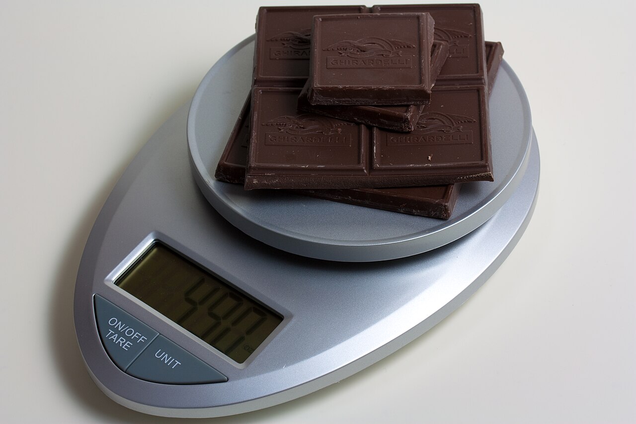 Pieces of chocolate on the platform of a digital kitchen scale.