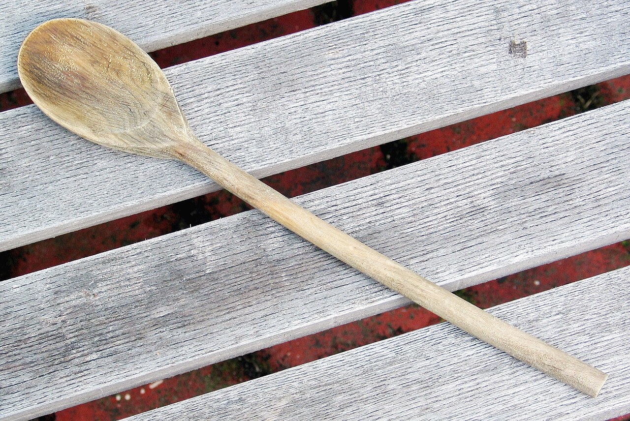 A well-used wooden cooking spoon with visible grain.